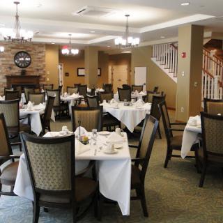 A neatly arranged dining room in a restaurant, featuring tables set with white linens and elegant chairs.