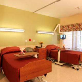 A modern hospital room with two beds and medical equipment.