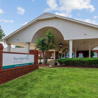 Exterior view of a building with a brick sign and landscaped lawn.