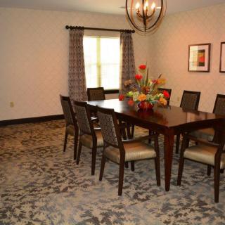 A cozy dining room with a large wooden table, matching chairs, and a decorative chandelier.