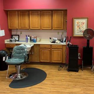 Interior of a barber shop with a styling chair, sink, and cabinets.