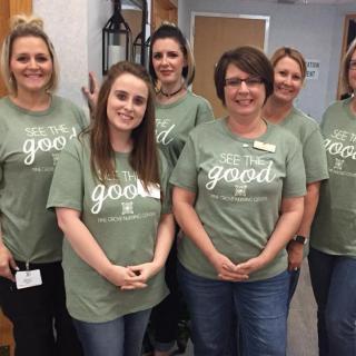 A group of women smiling and wearing matching green t-shirts indoors.