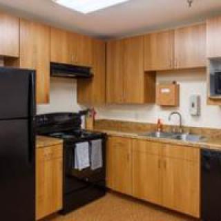 Modern kitchen with wooden cabinets and black appliances.