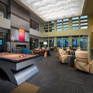 A modern lounge area featuring a pool table, comfortable seating, and large windows providing ample natural light.