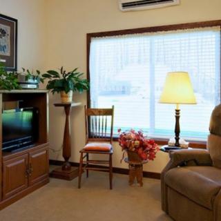 A cozy living room with a reclining chair, television, and lamp by a large window.