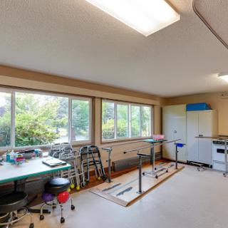 A bright and spacious room with tables and chairs, featuring large windows that bring in natural light.