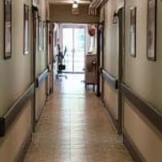A view down a long hallway with doors on either side leading to an open doorway at the end.