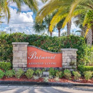 Entrance sign for the Balmoral gated community, surrounded by lush landscaping and palm trees.