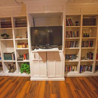 A cozy living room with built-in bookshelves surrounding a TV, set against a wooden floor.