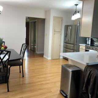 A modern kitchen and dining area with hardwood flooring and stainless steel appliances.