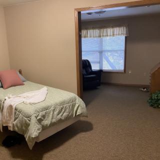 A simple bedroom with a single bed and an armchair by the window.