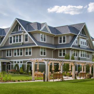 A beautiful multi-story residential house with a well-kept garden and pergola.