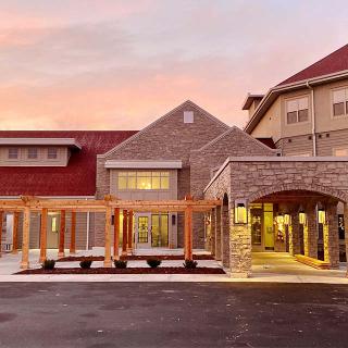 A modern building with a welcoming entrance is illuminated during sunset.