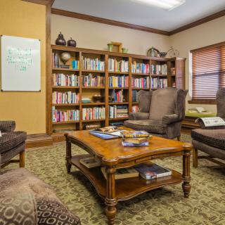 A cozy library room with comfortable seating and bookshelves.