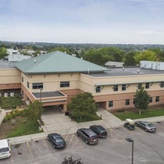 Aerial view of a large building with a green roof and adjacent parking lot.
