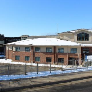A brick building surrounded by snow on a clear winter day.