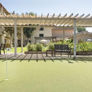 A tranquil outdoor space with a pergola and seating area overlooking a well-maintained lawn.