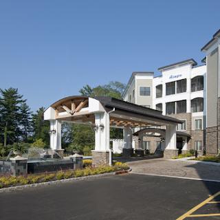 A modern hotel entrance showcasing elegant architecture surrounded by lush landscaping.