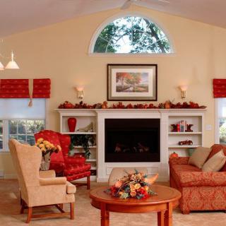 A cozy living room with autumn-themed decor, featuring a fireplace and comfortable seating.