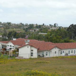 A view of a building with a red roof surrounded by grassy fields in a countryside setting.