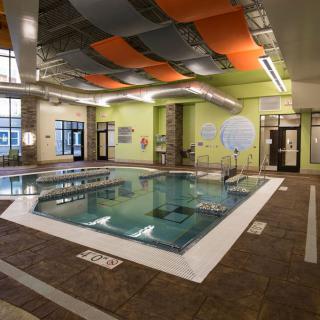 A modern indoor swimming pool with vibrant ceiling panels and a spacious layout.