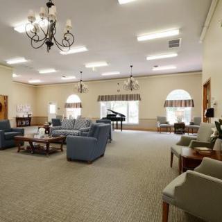 A spacious living room with comfortable seating and a piano.