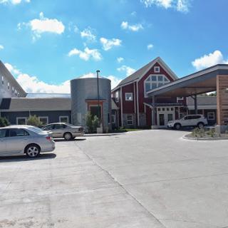 A modern commercial building with a parking area under a clear blue sky.