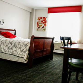 A cozy bedroom with a wooden bed, desk, and chair, featuring red accents.