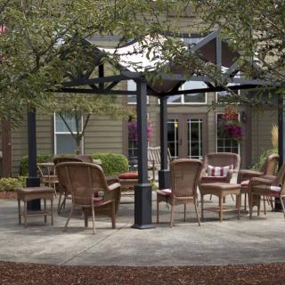 A cozy outdoor patio area with wicker chairs under a pergola.