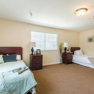 A cozy bedroom with two twin beds, bedside tables, and a window letting in natural light.