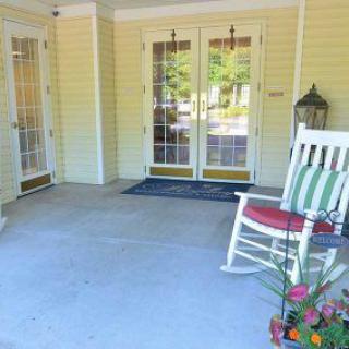 A cozy porch with a rocking chair and flowers near the entrance.