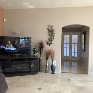 A cozy living room featuring a television, decorative vases, and an arched doorway on a tiled floor.