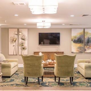 A cozy living room featuring comfortable seating, elegant artwork, and a large television.