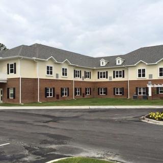 A two-story brick residential building under a cloudy sky.