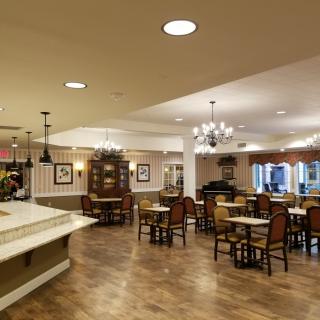 A cozy dining area with tables and chairs, featuring elegant lighting and decor.
