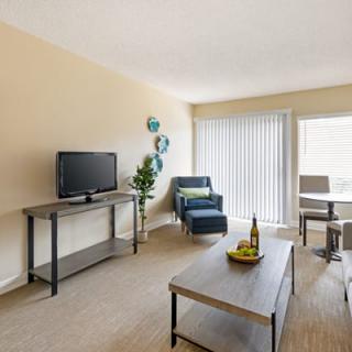 A modern living room with a television, comfortable seating, and bright natural light.