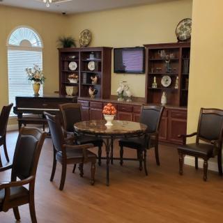 A cozy living room with elegant furniture, including a round table surrounded by chairs, and bookshelves adorned with decor items.