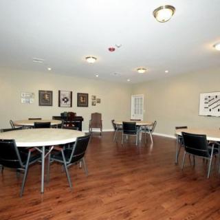 A spacious meeting room with round tables, chairs, and artwork on the walls.
