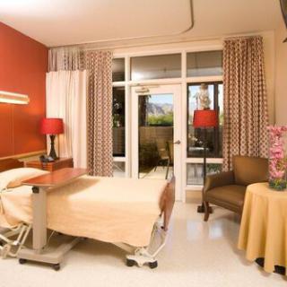 A well-furnished hospital room with a bed, stylish furniture, and decorative elements.