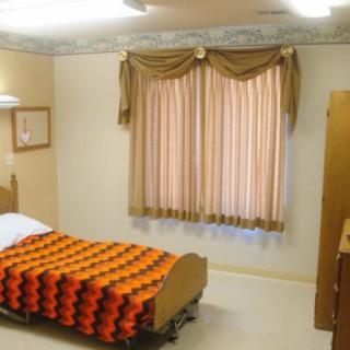 A simple bedroom with a patterned blanket on the bed and curtains covering the window.