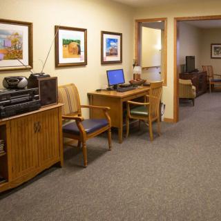 A cozy office interior featuring a computer workstation, chairs, and wall art.