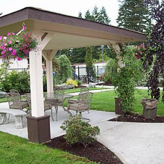 A well-maintained garden with a covered patio, featuring outdoor seating and lush greenery.