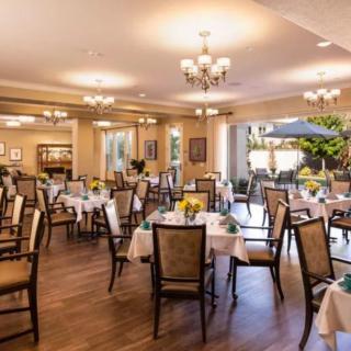 An elegant dining room with neatly arranged tables and chairs, illuminated by chandeliers.
