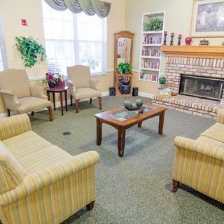 A cozy living room with comfortable chairs, a sofa, a coffee table, and a fireplace.