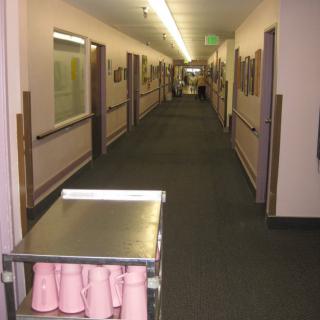 A long corridor with a trolley holding pink cups, likely in a healthcare facility.