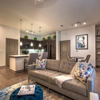 A modern, open-concept living space featuring a cozy sofa, stylish decor, and a kitchen with bar seating.
