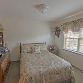 A cozy bedroom with a bed, dresser, and window with floral curtains.
