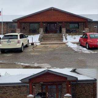 A view of a building's entrance surrounded by snow and parked cars.