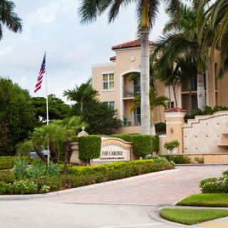 Entrance of a residential building with tropical landscaping and palm trees.