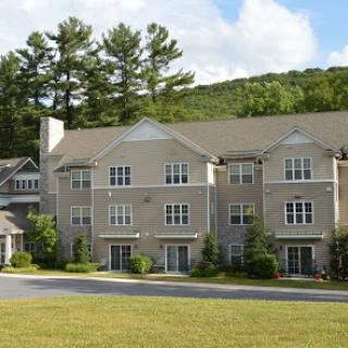 A picturesque residential building surrounded by lush greenery and mountains.